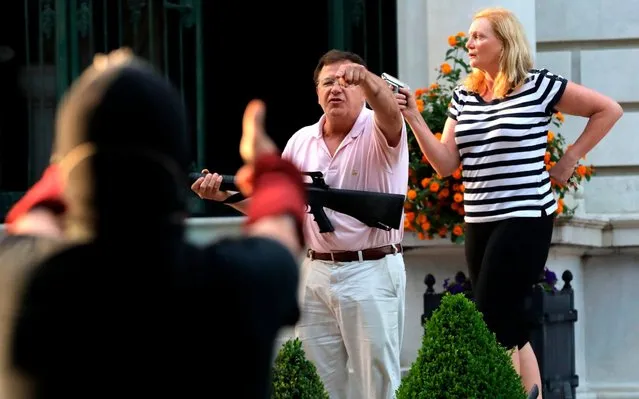 Armed homeowners standing in front their house on  Portland Place and confront protesters marching to St. Louis Mayor Lyda Krewson's house in Missouri, U.S. on June 28, 2020. The protesters called for Krewson's resignation for releasing the names and addresses of residents who suggested defunding the police department. (Photo by Laurie Skrivan/St. Louis Post)