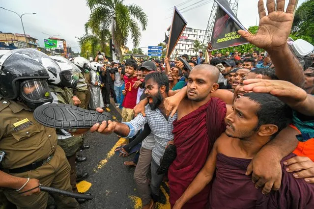 Protestors shout as policemen stand guard during an anti-government demonstration by the university students demanding the release of their leaders, in Colombo on October 18, 2022. (Photo by Ishara S. Kodikara/AFP Photo)