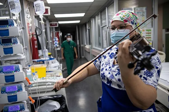 Chilean nurse Damaris Silva plays the violin for patients infected with COVID-19, at the Intensive Care Unit of the El Pino hospital, in Santiago, Chile, on July 9, 2020. (Photo by Martin Bernetti/AFP Photo)