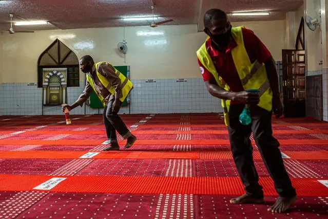 Staff spray disinfectant before a prayer at the Abubakar Mosque in Eastleigh, Nairobi, on July 14, 2020, as all worship places in Kenya resume their services with restrictions limiting 100 people per session in less than an hour. (Photo by Patrick Meinhardt/AFP Photo)