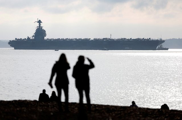 People watch from a nearby beach as the USS Gerald R Ford aircraft carrier enters the Solent near Gosport, Britain on November 14, 2022. (Photo by Peter Nicholls/Reuters)