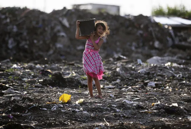 A Filipino girl carries a bucket filled with rocks which she gathered near her home in suburban Paranaque, south of Manila, Philippines, Sunday, September 6, 2015. The girl said the rocks would be used to build barriers to prevent floodwaters from entering her family home. (Photo by Aaron Favila/AP Photo)