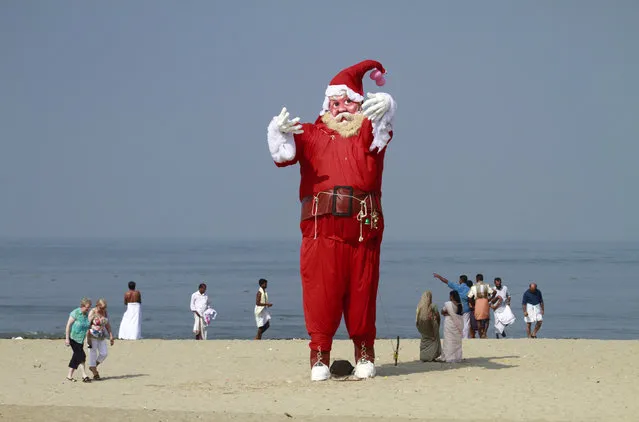 Tourists and locals walk past a Santa Claus statue placed on a beach for a film shoot in the southern Indian city of Kochi December 10, 2012. (Photo by Sivaram V/Reuters)