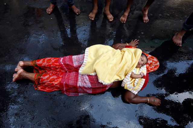 An infant lies on the back of a woman as she performs a ritual while worshipping Sheetala Mata, the Hindu goddess of smallpox, during Sheetala Puja in which people pray for the betterment of their family and society, in Kolkata, April 15, 2017. (Photo by Rupak De Chowdhuri/Reuters)