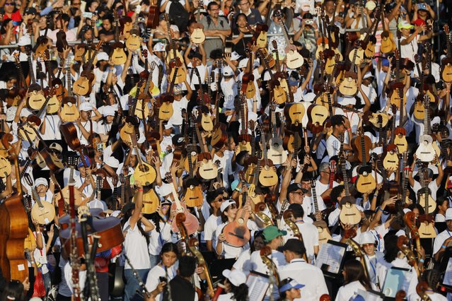 Youth raise their instruments during a concert celebrating the 50th anniversary of Venezuela's national system of children and youth orchestras in Caracas, Venezuela, Sunday, February 23, 2025. (Photo by Cristian Hernandez/AP Photo)