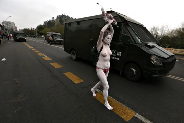 A half-naked demonstrator runs along a riot police vehicle as Human Rights activists march in Santiago, on September 11, 2016 commemorating the 43rd anniversary of the military coup led by General Augusto Pinochet that deposed President Salvador Allende. (Photo by Claudio Reyes/AFP Photo)