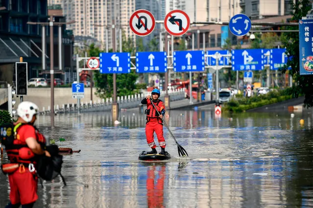 This photo taken on August 19, 2020 shows a rescuer paddling across a flooded street in China's southwestern Chongqing. Floods in mountainous southwest China have washed away roads and forced tens of thousands from their homes, with authorities warning on August 19 the giant Three Gorges Dam was facing the largest flood peak in its history. (Photo by AFP Photo/China Stringer Network)