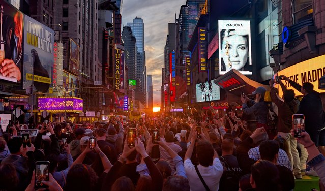 The sun breaks through cloud cover as people along 42nd Street photograph the Manhattanhenge sunset on May 29, 2025, in New York City. (Photo by Gary Hershorn/Getty Images)