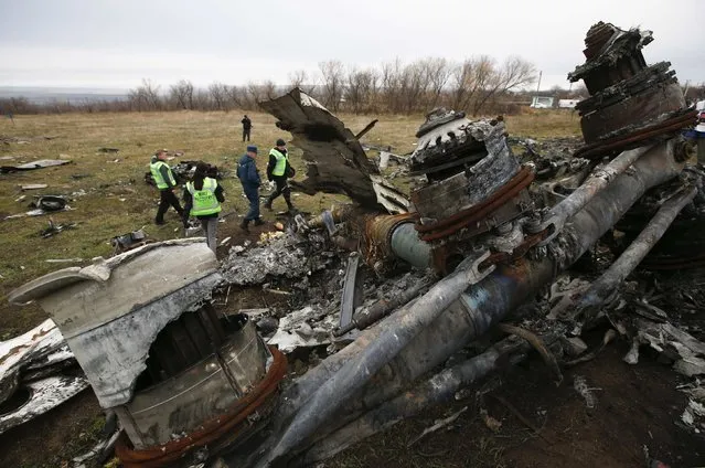 Dutch investigators and an Emergencies Ministry member work at the site where the downed Malaysia Airlines flight MH17 crashed, near the village of Hrabove (Grabovo) in Donetsk region, eastern Ukraine November 16, 2014. (Photo by Maxim Zmeyev/Reuters)