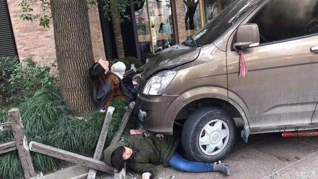 Pedestrians are pinned in front of a minivan that crashed up on a sidewalk, Friday, February 2, 2018, in downtown Shanghai, China. A minivan plowed into pedestrians on a sidewalk in downtown Shanghai on Friday, sending more than a dozen people to hospitals. (Photo by Gao Yan/AP Photo)
