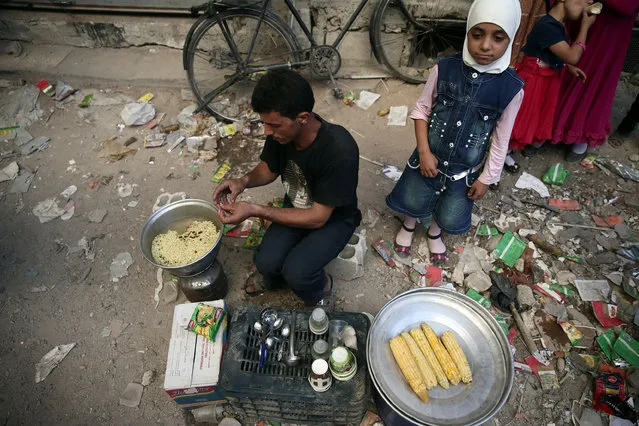 A vendor sells corn on the cob and noodles on the last day of Eid al-Adha celebrations in the rebel held besieged town of Hamouriyeh, eastern Ghouta, near Damascus, Syria September 15, 2016. (Photo by Bassam Khabieh/Reuters)