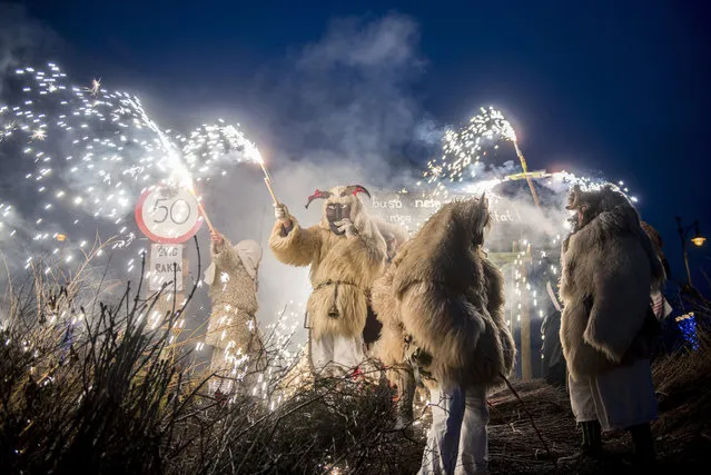 Revelers wearing sheepfur costume lit a bonfire to burn a coffin, symbolizing winter, during the closing ceremony of the traditional carnival parade in Mohacs, 189 kms south of Budapest, Hungary, 13 February 2018. The carnival parade of people, the so-called busos, dressed in sheepfur costumes and frightening wooden masks, using various noisy wooden rattlers is traditionally held on the seventh weekend before Easter to drive away winter. The parade is a revival of a legend, which says that ethnic Croats ambushed the Osmanli Turkish troops, who escaped in panic seeing the terrifying figures during the Turkish occupation of Hungary. (Photo by Tamas Soki/EPA/EFE)