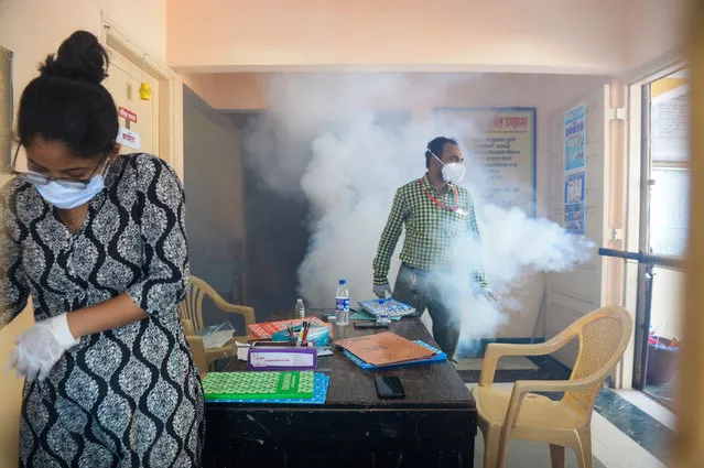 A man is covered in smoke as a woman reacts during fumigation by civic authority at a Covid-19 coronavirus isolation centre as a preventive measure against diseases-carrying mosquitoes during the monsoon season in Mumbai on September 28, 2020. (Photo by Indranil Mukherjee/AFP Photo)