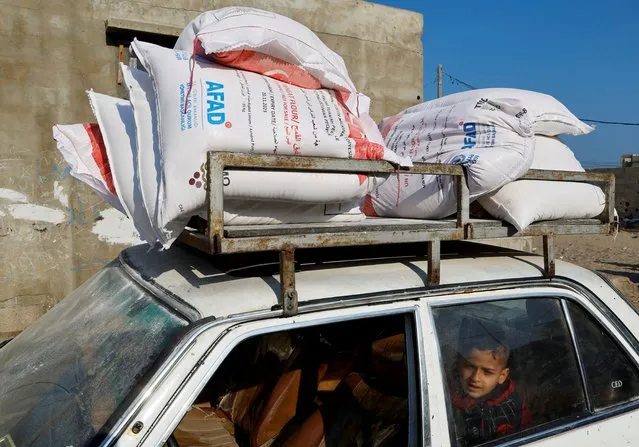 A Palestinian boy sits in a car after receiving aid at a United Nations food distribution center in Al-Shati refugee camp in Gaza City on January 25, 2023. (Photo by Mohammed Salem/Reuters)