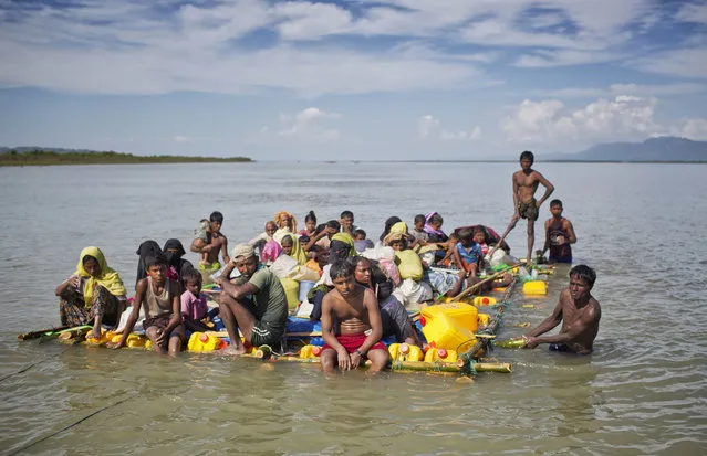 In this November 11, 2017 file photo, Rohingya Muslims travel on a raft made with plastic containers on which they crossed over the Naf river from Myanmar into Bangladesh, near Shah Porir Dwip, Bangladesh. Six months after waves of attacks emptied Rohingya villages in Myanmar, sending 700,000 people fleeing into Bangladesh, there are few signs anyone is going home soon. Life isn’t easy in the refugee camps, but the Rohingya living there have one immense consolation. “Nobody is coming to kill us, that’s for sure”, says one man. (Photo by A.M. Ahad/AP Photo)