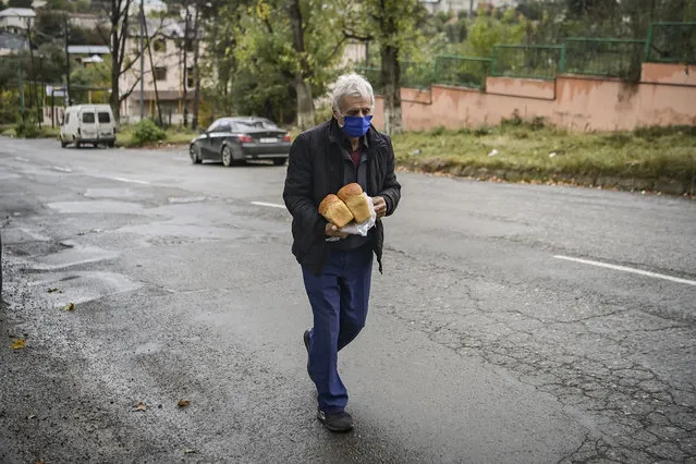 An elderly man walks on a street after receiving free bread from a bakery in the city of Stepanakert, that works 24 hours a day to offer bread to the remain residents and delivering – when needed – to the cities of Martuni and Martakert, on October 21, 2020, during the ongoing fighting between Armenia and Azerbaijan over the breakaway region of Nagorno-Karabakh. (Photo by Aris Messinis/AFP Photo)