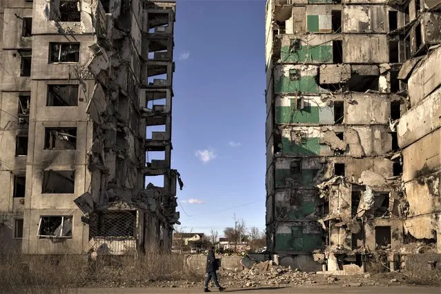 A man walks by an apartment block missing its central section after being hit by an airstrike, one year ago, in Borodyanka, Ukraine, Thursday, March 2, 2023. (Photo by Vadim Ghirda/AP Photo)