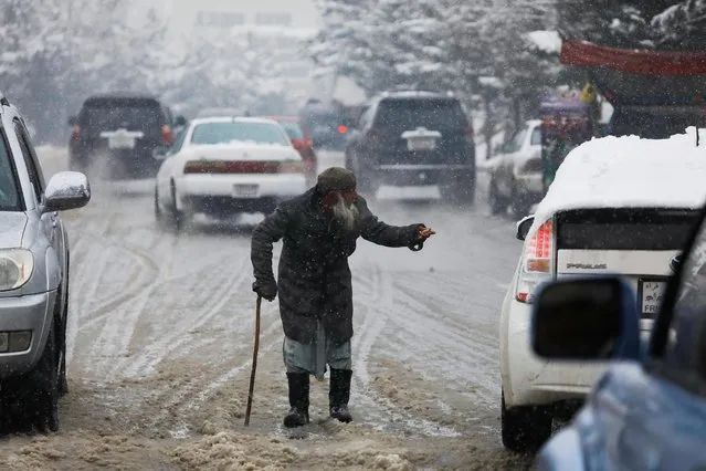 An Afghan man begs on a snowy day in Kabul, Afghanistan on January 29, 2023. (Photo by Ali Khara/Reuters)