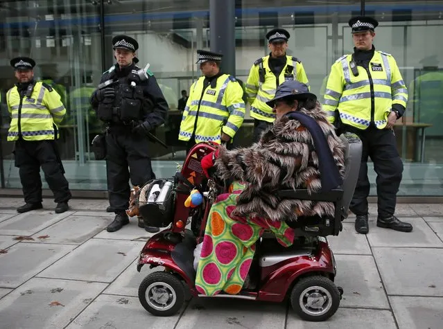 A woman rides her mobility scooter past police protecting a building during a student demonstration protesting cuts to grants, in London, Britain November 4, 2015. (Photo by Stefan Wermuth/Reuters)