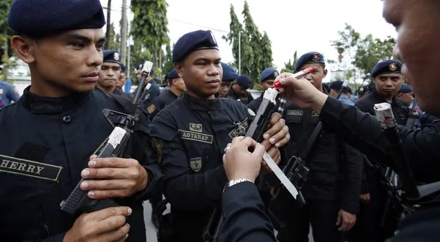 A Philippine National Police (PNP) SWAT team leader (R) signs a sealed muzzles of the firearms of his men at the National Capital Region Police Office in Taguig, Metro Manila, December 22, 2014. (Photo by Erik De Castro/Reuters)
