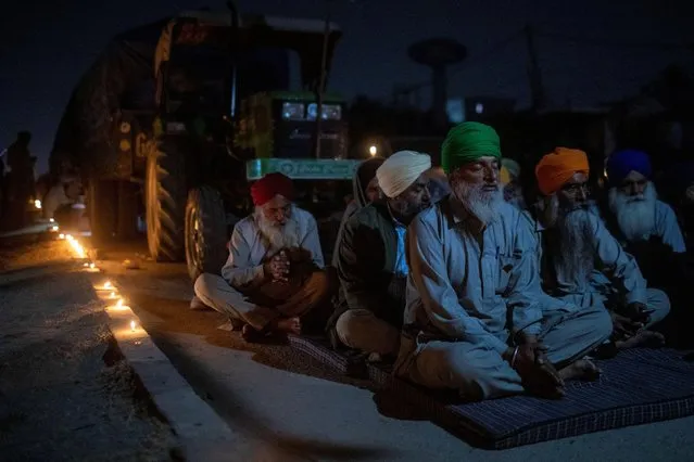 Farmers pray to mark the 551st birth anniversary of Guru Nanak Dev, the first Sikh Guru and founder of Sikh faith, at the site of a protest against the newly passed farm bills at Singhu border near Delhi, India, November 30, 2020. (Photo by Danish Siddiqui/Reuters)