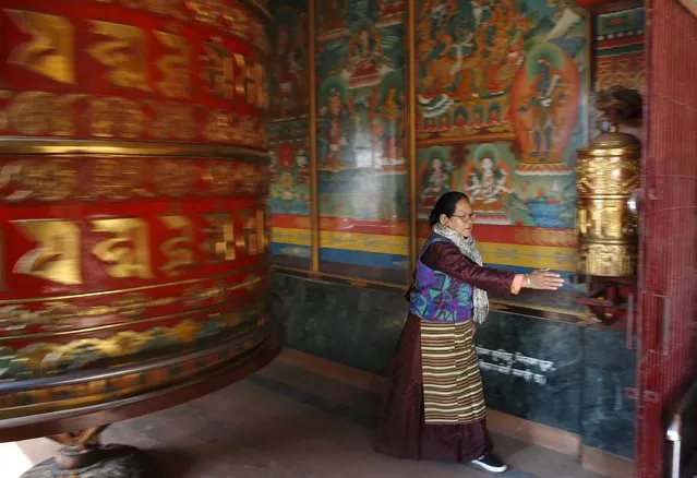 A Buddhist devotee spins prayer wheels while offering daily prayers at the premises of Boudhanath Stupa in Kathmandu December 23, 2014. Listed as a world heritage site by UNESCO, the Boudhanath Stupa is considered one of the holiest places for Buddhists. (Photo by Navesh Chitrakar/Reuters)