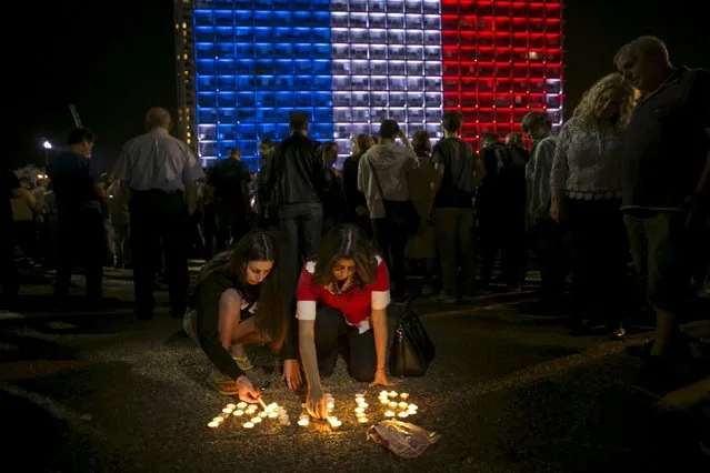 Israelis light candles during a ceremony honouring victims of the attacks in Paris, as the Tel Aviv municipality is lit up in the blue, white and red colours of the French flag, November 14, 2015. (Photo by Baz Ratner/Reuters)
