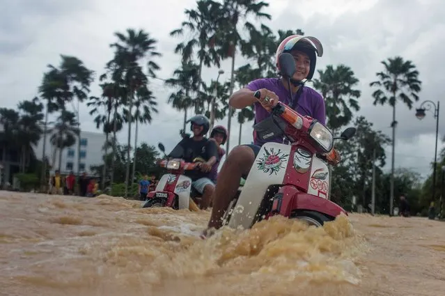 Local residents use their motorbikes to maneuver through floodwaters in Kota Bahru on December 28, 2014. (Photo by Mohd Rasfan/AFP Photo)