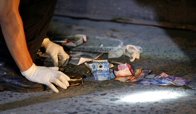 A police investigator makes an inventory of the money found near the body of Herman Cunanan, who police said was killed by men riding in two motorcycles, in Quezon city, Metro Manila, Philippines October 19, 2016. Cunanan was a drug user, his unidentified live-in partner told reporters. (Photo by Erik De Castro/Reuters)
