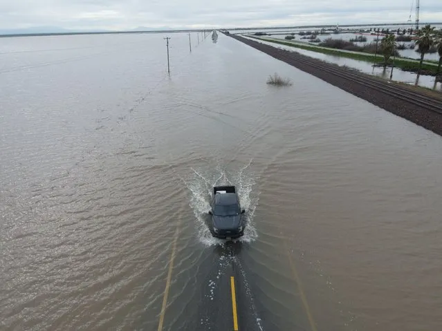A truck passes on a road as floodwaters from the Tule River inundate the area after days of heavy rain in Corcoran, California, U.S., March 22, 2023. (Photo by David Swanson/Reuters)