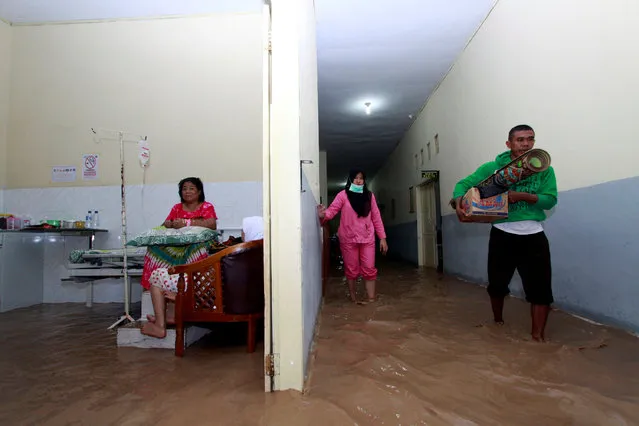 A man walks while carrying his belongings as floods inundate the treatment rooms at the MM Dunda hospital after heavy rain in Gorontalo Regency, Indonesia, October 25, 2016. (Photo by Adiwinata Solihin/Reuters/Antara Foto)