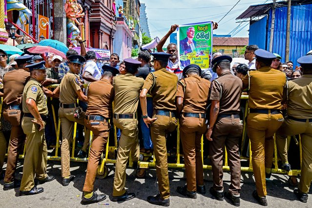 Police restrain supporters of Sri Lanka's jailed former president Ranil Wickremesinghe during a protest ahead of his bail hearing at a street leading to the Colombo Fort magistrate's court in Colombo on August 26, 2025. (Photo by Ishara S. Kodikara/AFP Photo)