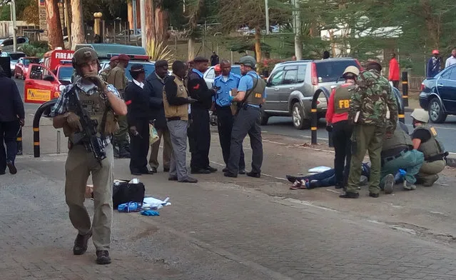 Unidentified U.S. Embassy personnel and Kenyan security forces stand near to the body, right, of a man who was killed outside the U.S. Embassy in Nairobi, Kenya Thursday, October 27, 2016. A Kenyan police official said the man was shot dead after stabbing a policeman guarding the perimeter wall of the U.S. Embassy in Nairobi. (Photo by Moses Muoki/AP Photo)