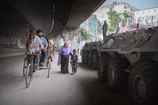 Pedestrians pass military tanks following protests in Dhaka, Bangladesh, on Wednesday, July 24, 2024. Bangladesh relaxed a nationwide curfew after deadly protests last week, allowing the key garment export sector and banks to reopen as the government tries to get the economy back on track and stem the declines in foreign exchange reserves. (Photo by Fabeha Monir/Bloomberg via Getty Images)