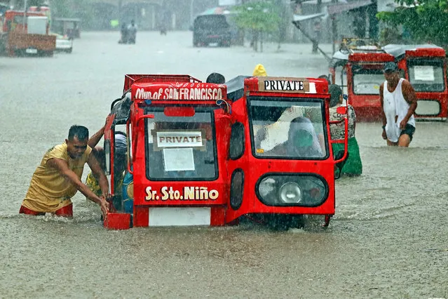 People push a half-submerged tricycle through a flooded street due to heavy rains caused by tropical depression Vicky in San Francisco town, Agusan del sur province on the southern island of Mindanao on December 18, 2020. (Photo by Erwin Mascarinas/AFP Photo)