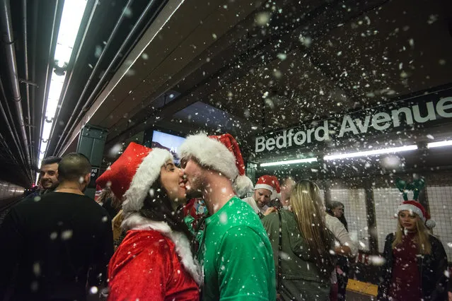 Two people dressed as a Santa share a kiss on the subway platform during the annual SantaCon pub crawl December 12, 2015 in the Brooklyn borough of New York City. (Photo by Stephanie Keith/Getty Images)