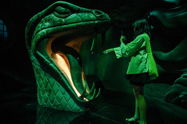 A woman takes a photo with a magic wand as she visits the exhibition “Harry Potter: Visions of Magic interactive” at Resort World Sentosa in Singapore on November 20, 2024. (Photo by Roslan Rahman/AFP Photo)