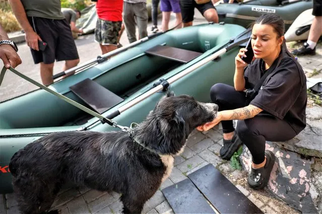 A volunteer plays with a dog, after the evacuation of pets from a flooded area after the Nova Kakhovka dam breached, amid Russia's attack on Ukraine, in Kherson, Ukraine on June 7, 2023. (Photo by Alina Smutko/Reuters)