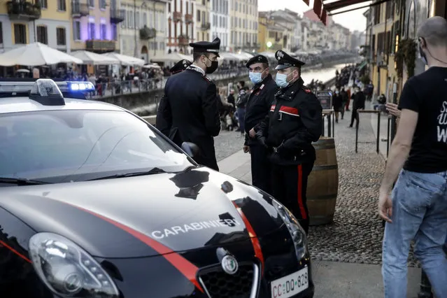 Carabinieri, Italian police officers, patrol the Naviglio Grande canal, in Milan, Italy, Saturday, February 27, 2021. Police vans blocked entrance to Milan's trendy Navigli neighborhood Saturday evening after the mayor announced increased patrols to prevent gatherings during a spring-like weekend. The Lombardy region where Milan is located is heading toward a partial lockdown on Monday, and Mayor Giuseppe Sala said in a video message that he was disturbed by scenes of people gathering in public places, often with their masks down. (Photo by Luca Bruno/AP Photo)