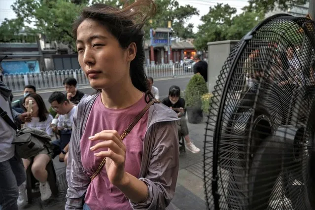 A woman cools herself on a misting fan as she waits for a table outside a popular local restaurant during a heatwave on June 23, 2023 in Beijing, China. Authorities issued a red alert for high temperatures, the highest in the country's four tier system, as China's capital and other parts of northern China saw scorching temperatures hovering around 40 degrees Celsius. (Photo by Kevin Frayer/Getty Images)