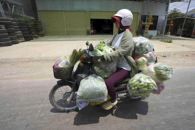 A vendor on a motorbike carries fresh vegetables through a main road for selling at local market outside Phnom Penh Cambodia, Thursday, March 16, 2023. (Phoot by Heng Sinith/AP Photo)