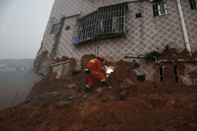 A firefighter uses a flashlight to search for survivors at a damaged building at the site of a landslide at an industrial park in Shenzhen, Guangzhou, China, December 20, 2015. (Photo by Tyrone Siu/Reuters)