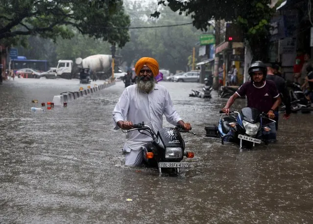 A man on his motorbike wades through a flooded street after heavy rains in New Delhi, India on July 8, 2023. (Photo by Anushree Fadnavis/Reuters)