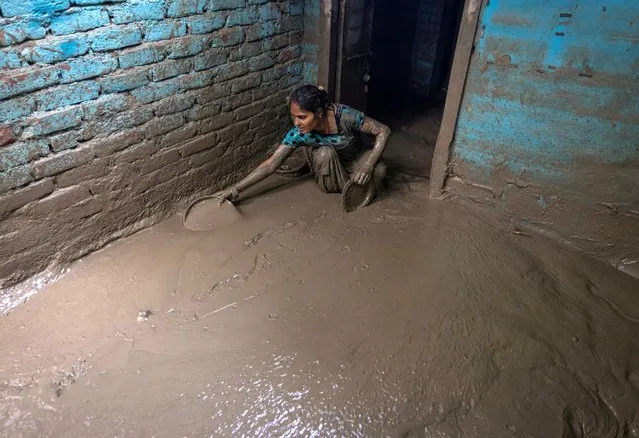 Munni Devi, 28, cleans the mud from the entrance of her house as flood water recedes from a residential area that was flooded by the overflowing of the river Yamuna following heavy rains, in New Delhi, India on July 17, 2023. (Photo by Adnan Abidi/Reuters)