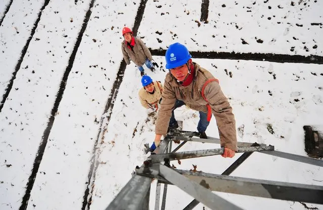 Employees check on a pylon as it snows in Hefei, Anhui province, January 28, 2015. China plans to cut its growth target to around 7 percent in 2015, its lowest goal in 11 years, sources said, as policymakers try to manage slowing growth, job creation and pursuing reforms intended to make the economy more driven by market forces. (Photo by Reuters/Stringer)