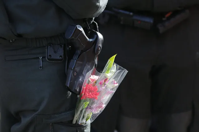 A police officer with flowers in her pocket stands guard during the traditional Rose Monday carnival parade in the western German city of Duesseldorf February 16, 2015. (Photo by Wolfgang Rattay/Reuters)