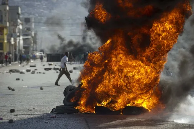 Protesters burn tires during a march against the government of Haitian President Michel Martelly in Port-au-Prince, on January 11, 2015. (Photo by Hector Retamal/AFP Photo)