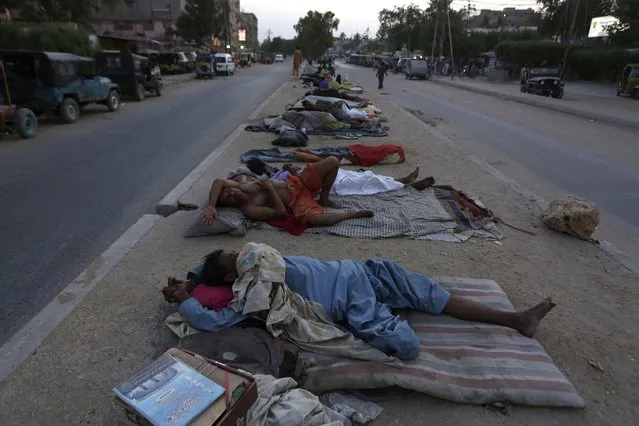 Laborers sleep in the open in the early hot summer morning in Karachi, Pakistan, Tuesday, May 18, 2021. Pakistani port city Karachi and some other parts of the country continued to experience an intense heat wave in these days. (Photo by Fareed Khan/AP Photo)