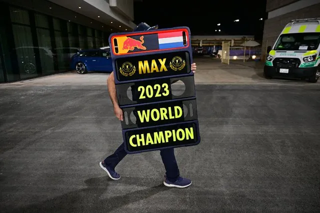 A Red Bull Racing team member carries a sign bearing the name of 2023 world champion Max Verstappen after the sprint race ahead of the Qatari Formula One Grand Prix at the Lusail International Circuit on October 7, 2023. (Photo by Ben Stansall/AFP Photo)