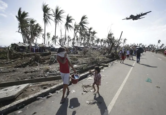 Survivors look up at a military C-130 plane as it arrives at typhoon-ravaged Tacloban city, Leyte province in central Philippines on Monday, November 11, 2013. Haiyan slammed the island nation with a storm surge two stories high and some of the highest winds ever measured in a tropical cyclone. An untold number of homes were blown away, and thousands of people are feared dead. (Photo by Aaron Favila/AP Photo)